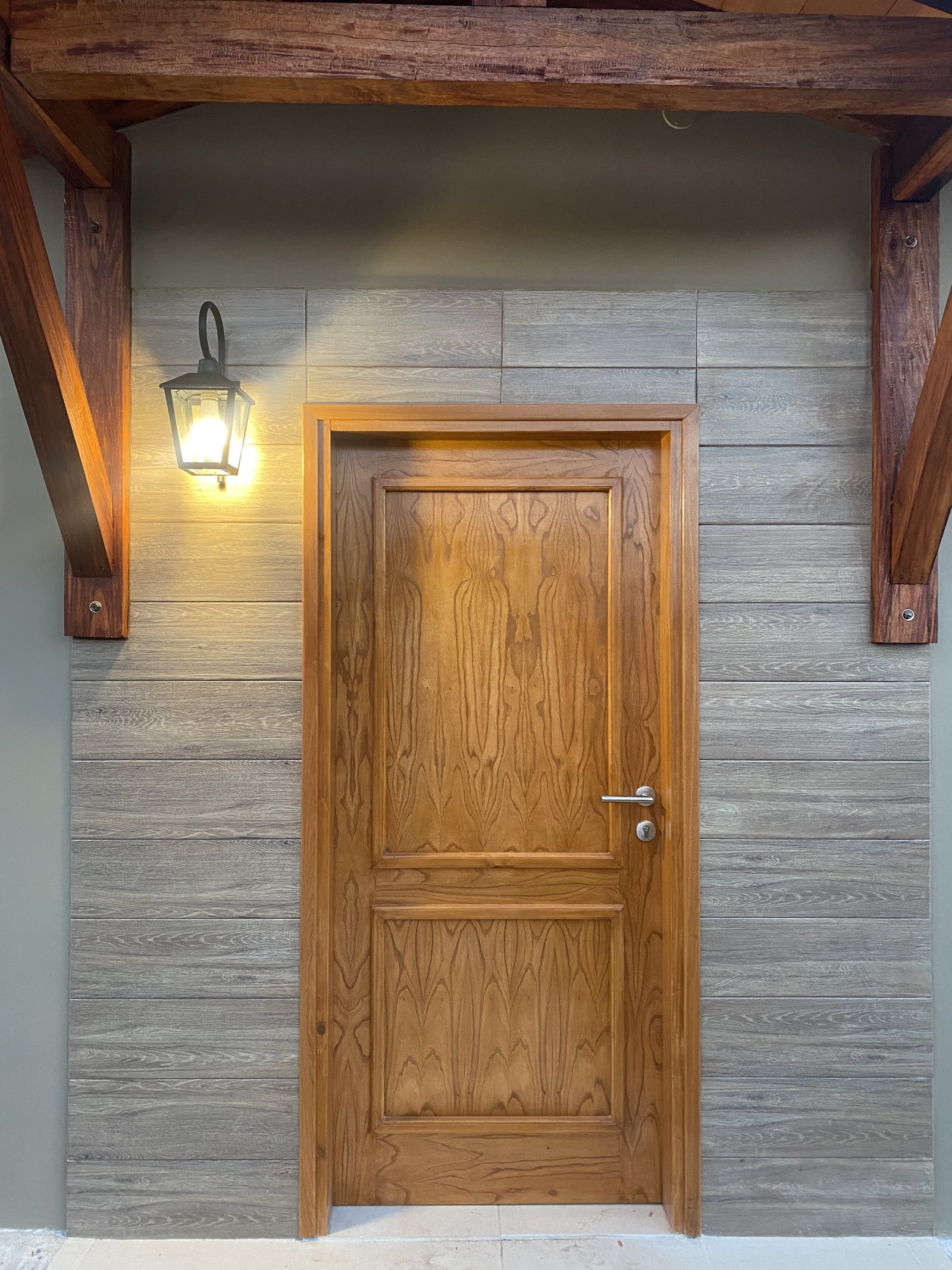Puerta de madera enmarcada en revestimiento simil piedra, San Lorenzo - OGA Constructora