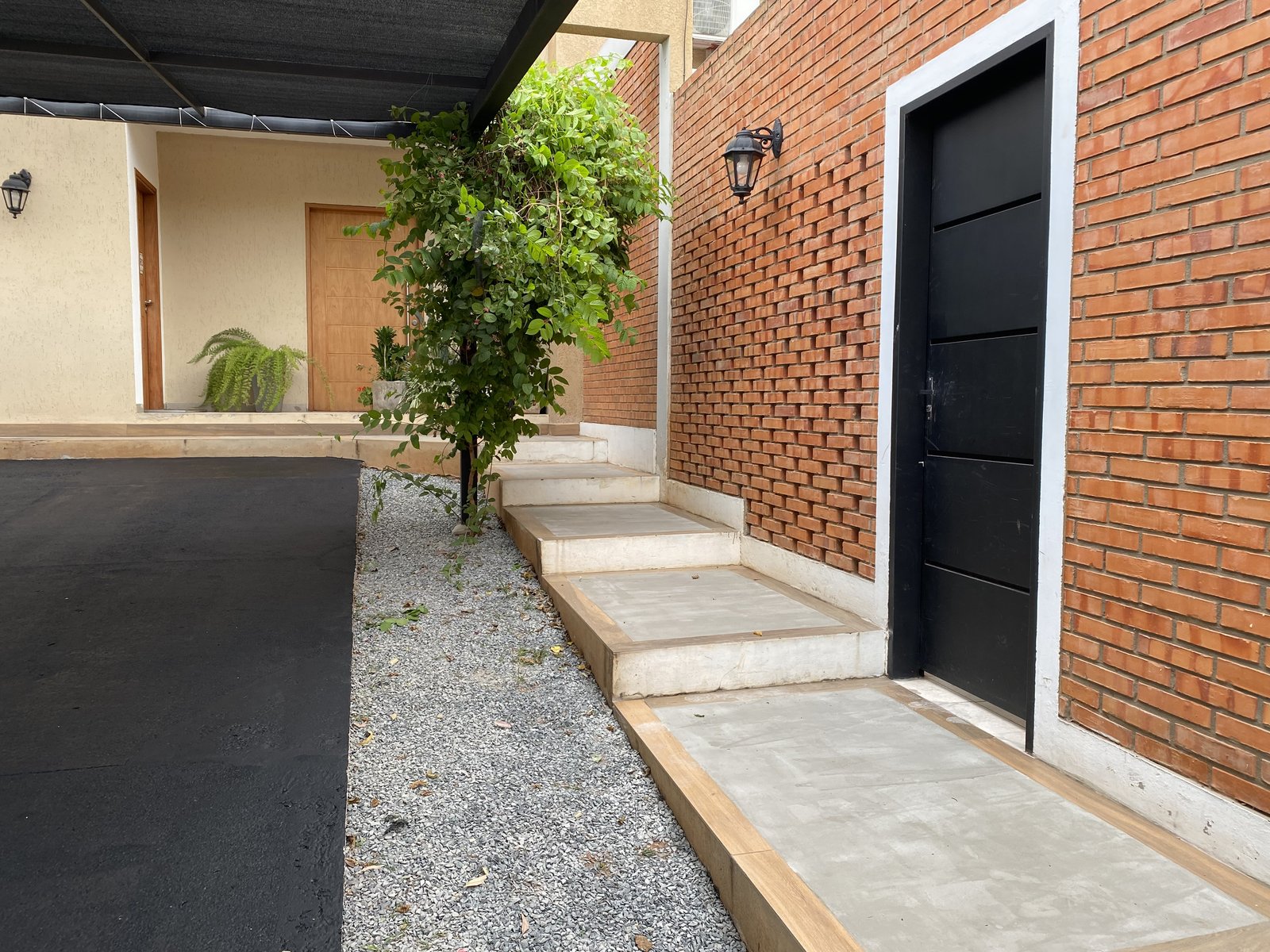 Acceso con muro de ladrillo de la vivienda, Loma Pyta - OGA Constructora