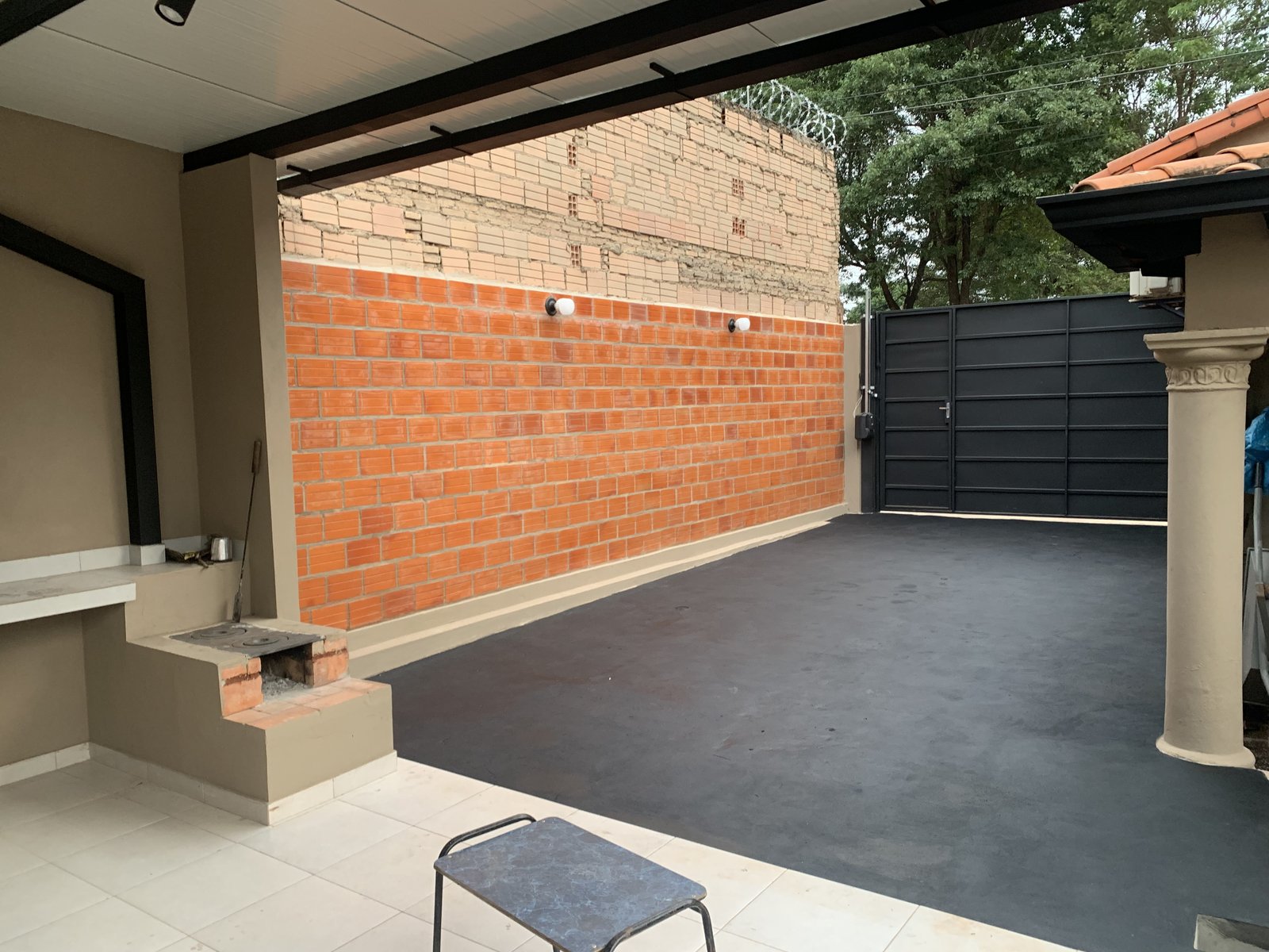 Quincho con muro de ladrillo y piso oscuro bajo techo metalico, San Lorenzo - OGA Constructora