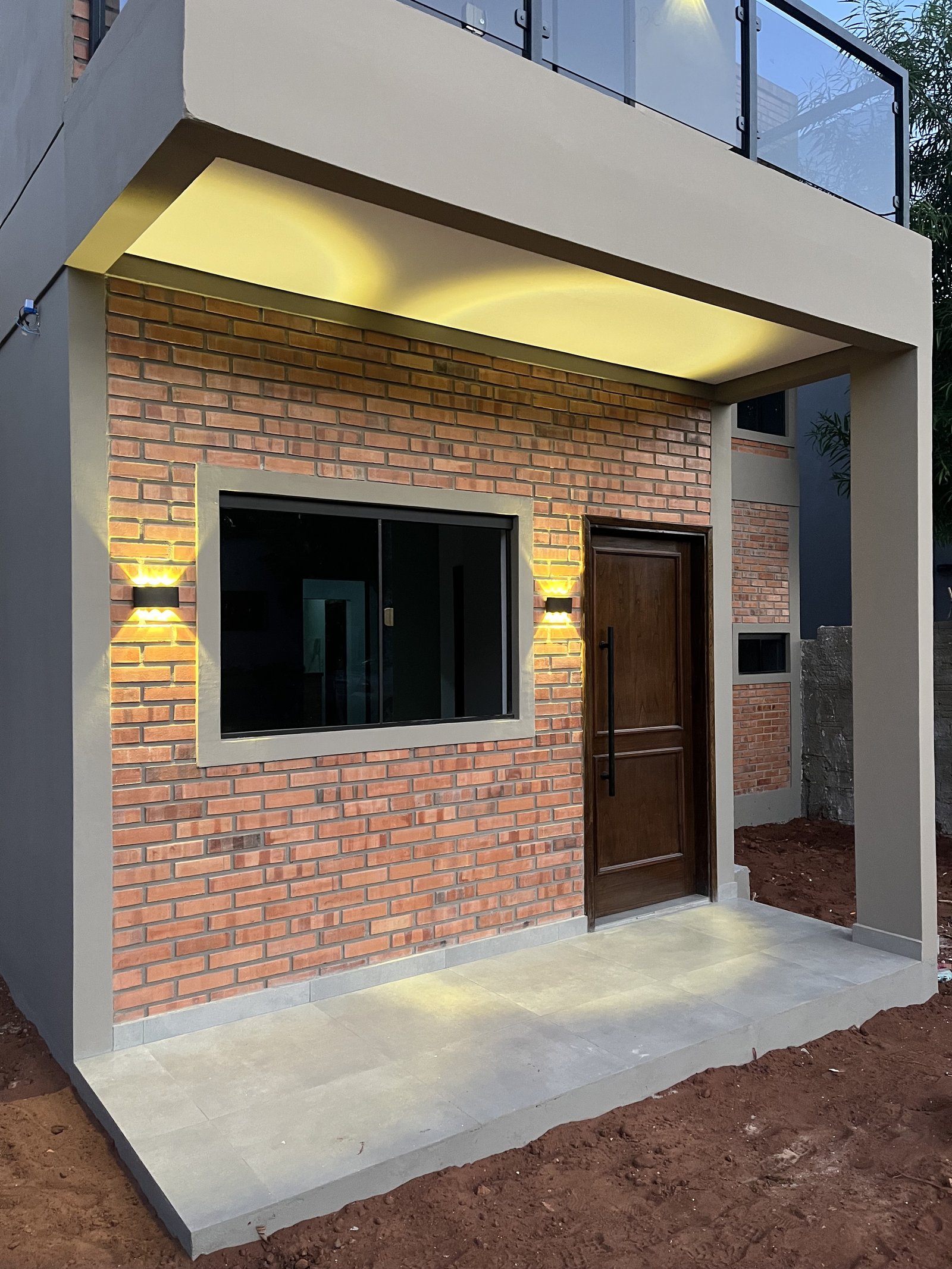Detalle de fachada en ladrillo visto con iluminacion perimetral calida, vivienda Mile San Lorenzo - OGA Constructora