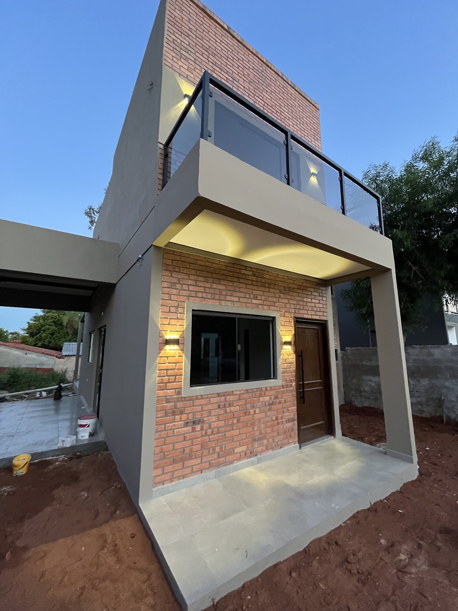 Esquina de vivienda de dos plantas en ladrillo visto y revoque blanco, San Lorenzo - OGA Constructora