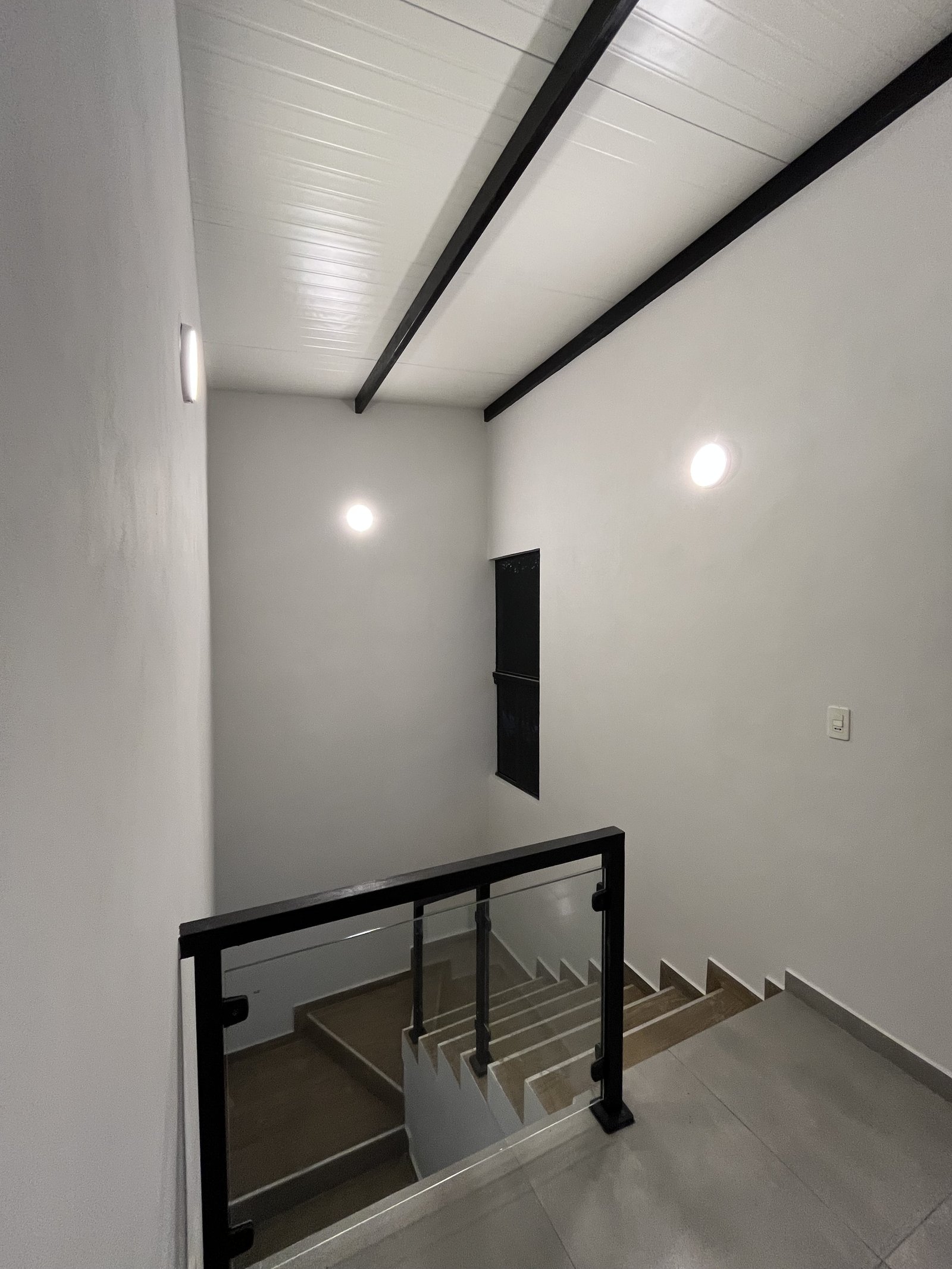 Escalera con baranda metalica negra y entrepiso, vivienda Mile San Lorenzo - OGA Constructora