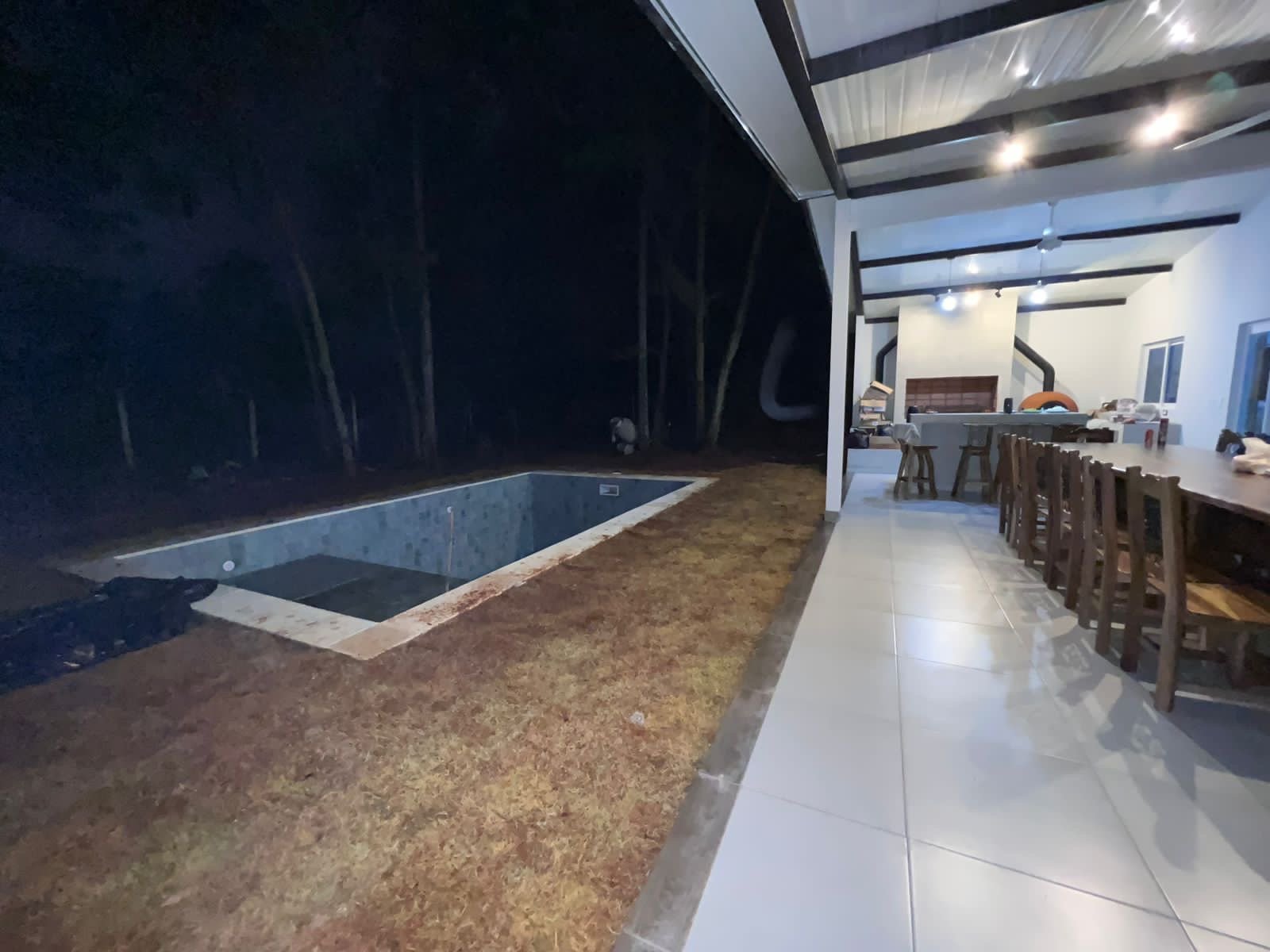Sector de piscina y quincho techado en penumbra, vivienda Yaguaron - OGA Constructora