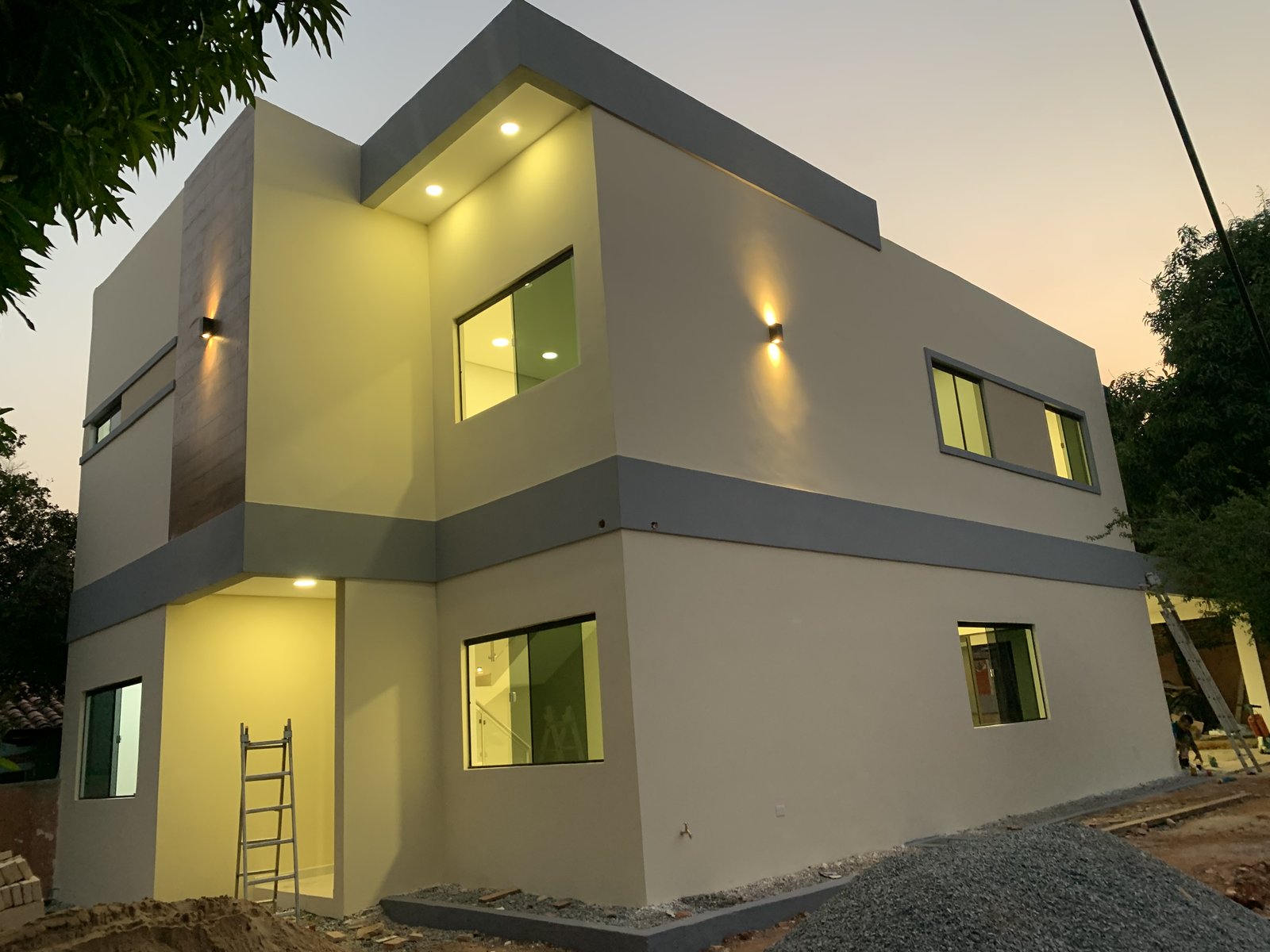 Fachada moderna de dos plantas iluminada al atardecer, vivienda Ruben Aranda Luque - OGA Constructora
