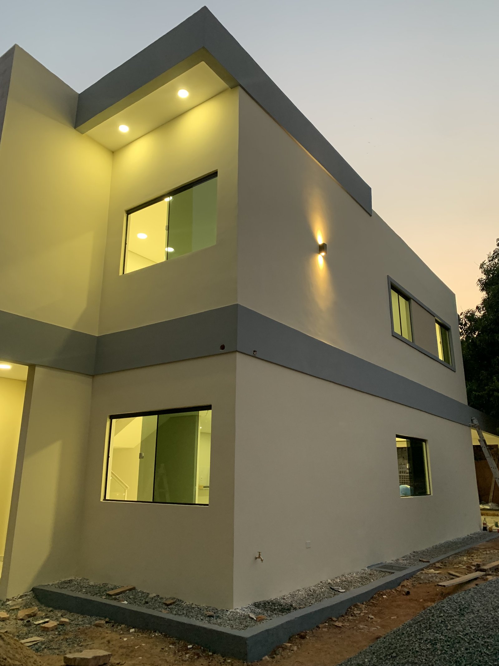 Ventanales iluminados de la vivienda Ruben Aranda al anochecer, Luque - OGA Constructora
