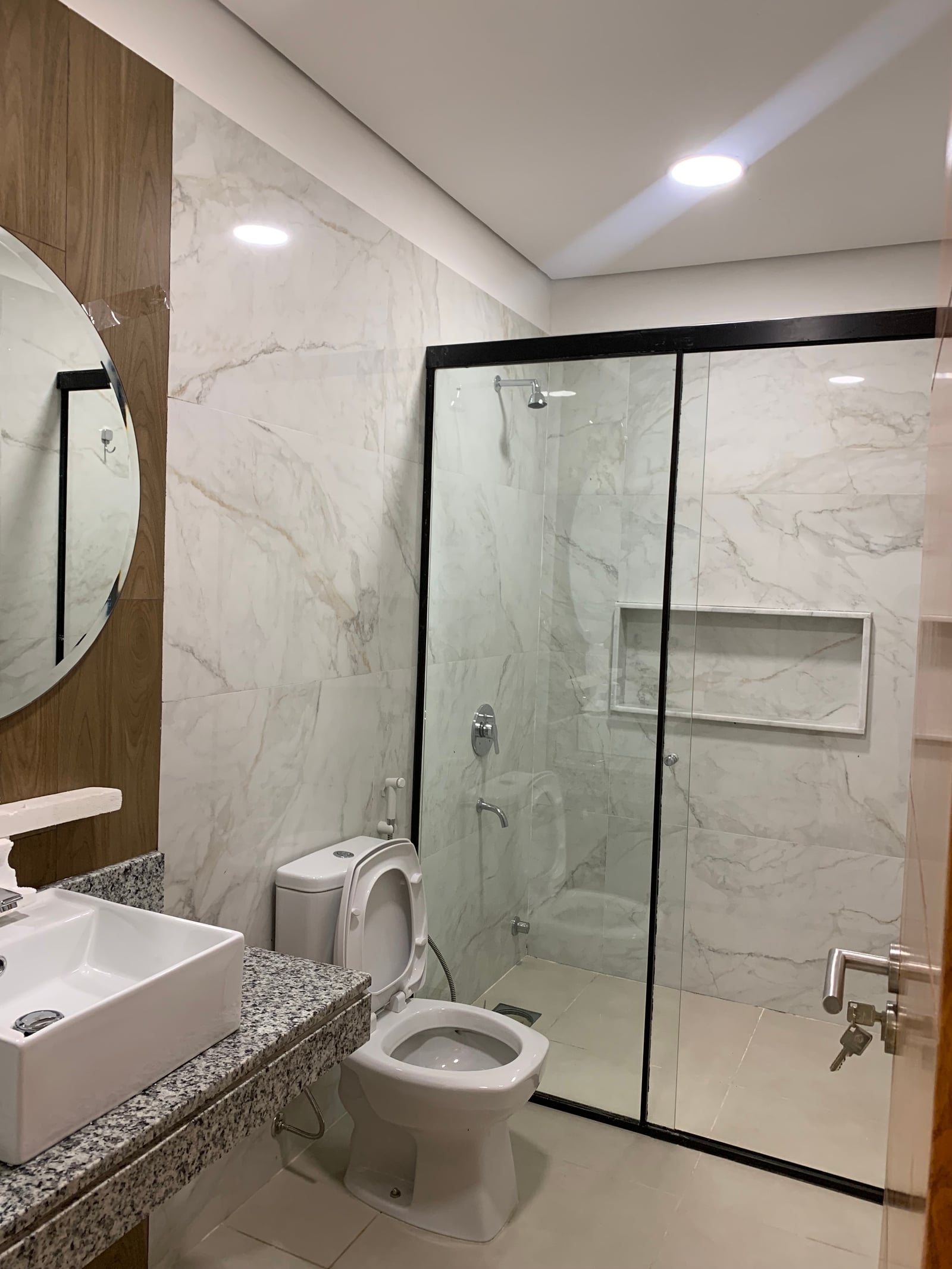 Bano con box de vidrio y revestimiento de marmol, vivienda Ruben Aranda Luque - OGA Constructora
