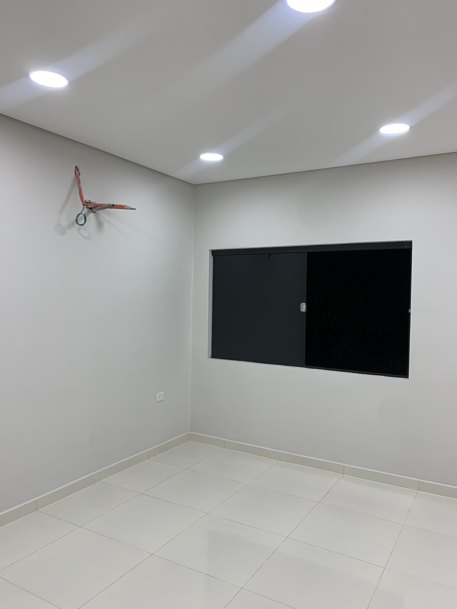 Ambiente interior blanco con television y ventilador de techo, vivienda Ruben Aranda Luque - OGA Constructora