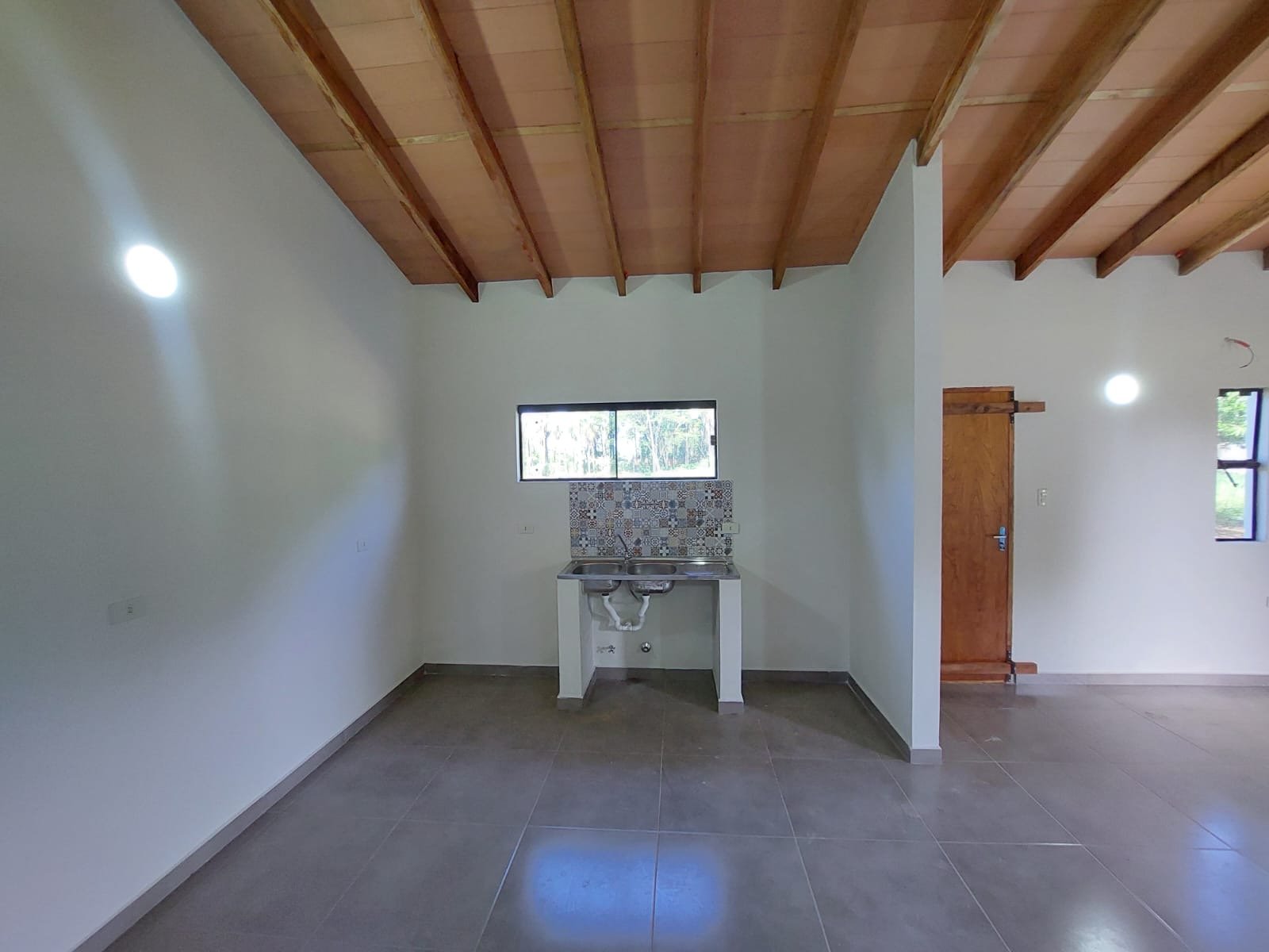 Ambiente interior con cielorraso de madera y ventana, vivienda Luque - OGA Constructora